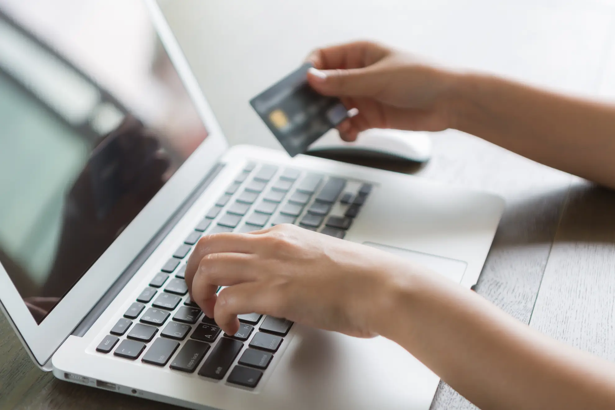 Person writing laptop with credit card